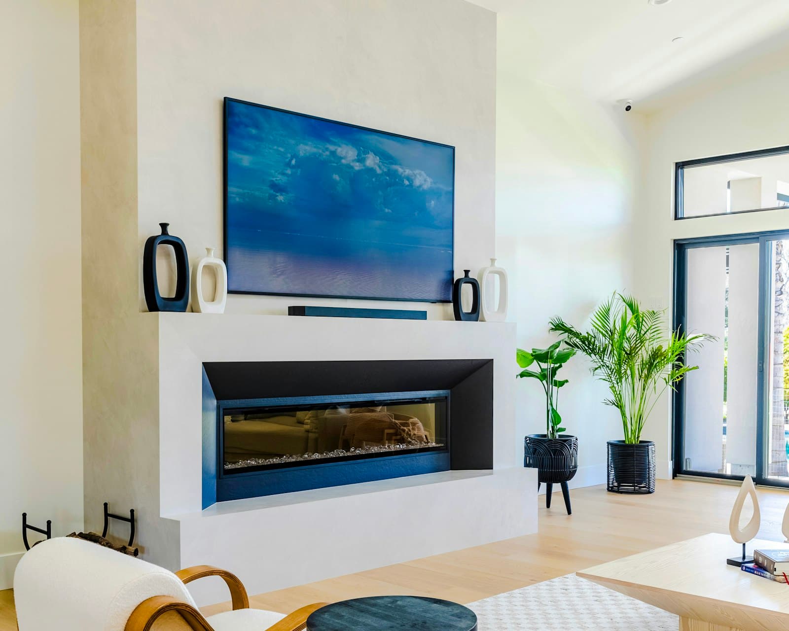 Flat-screen TV mounted centered above a linear gas fireplace on a smooth plaster chimney wall