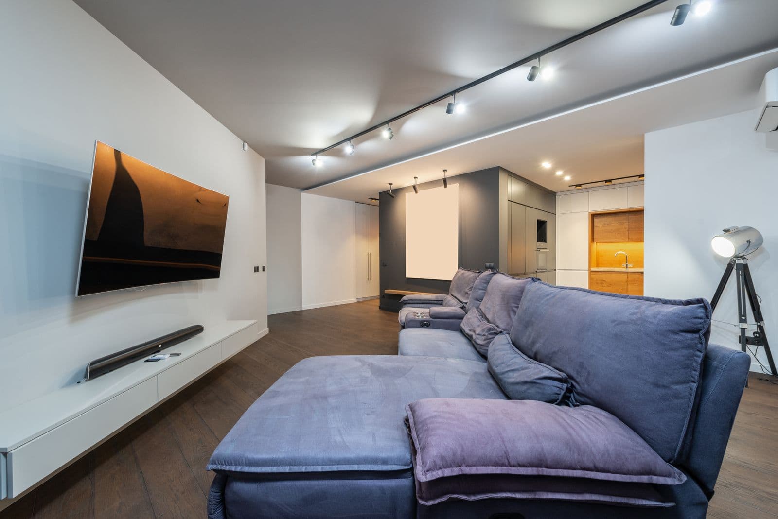Curved TV mounted on a white wall with a soundbar on the floating console below it